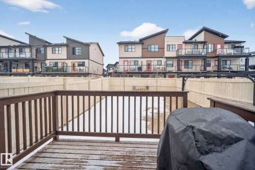 The property features a wooden deck with railing, overlooking a fenced yard - 1014 162 St Sw, Edmonton, AB - Outdoor With Deck Patio Veranda