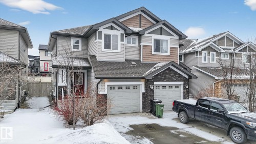 The property features a two-story exterior with light gray siding, dark stone accents, and a dual garage - 1014 162 St Sw, Edmonton, AB - Outdoor With Facade