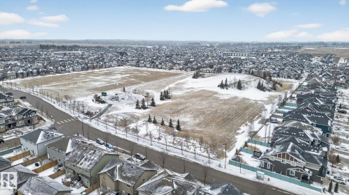 Aerial view of the surrounding neighborhood, featuring a large open field, residential properties with dark roofs, and roads - 1014 162 St Sw, Edmonton, AB - Outdoor With View
