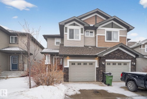 The property features a multi-toned exterior with siding and stone accents, a multi-car garage, and a peaked roofline - 1014 162 St Sw, Edmonton, AB - Outdoor With Facade