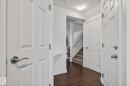 The entrance area features rich hardwood flooring and white paneled doors, leading to a carpeted staircase with white railings - 1014 162 St Sw, Edmonton, AB  - Indoor Photo Showing Other Room 