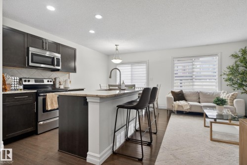 The property features a bright and open living area with hardwood flooring, recessed lighting, and white walls - 1014 162 St Sw, Edmonton, AB - Indoor Photo Showing Kitchen With Upgraded Kitchen