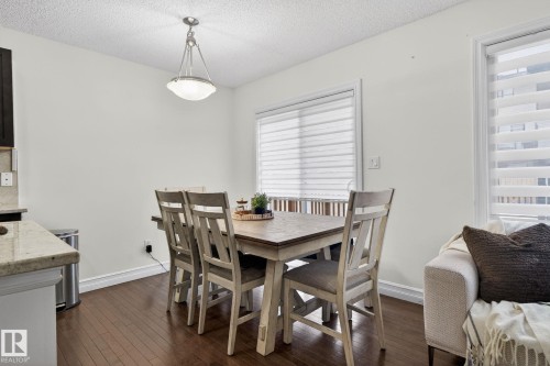 The property features hardwood floors, a modern light fixture, and windows with horizontal blinds - 1014 162 St Sw, Edmonton, AB - Indoor Photo Showing Dining Room