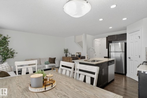 This property features an open-concept living area with hardwood floors, a kitchen island with granite countertops, and stainless steel appliances - 1014 162 St Sw, Edmonton, AB - Indoor Photo Showing Kitchen