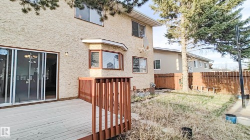 Rear exterior featuring a spacious wooden deck with railings, stucco siding, a bay window, and sliding glass patio doors - 3031 79 Street Nw, Edmonton, AB - Outdoor With Deck Patio Veranda