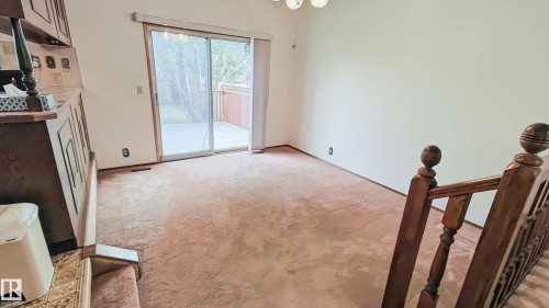 Carpeted interior space featuring a sliding glass door opening to an outdoor deck and yard - 3031 79 Street Nw, Edmonton, AB - Indoor Photo Showing Other Room