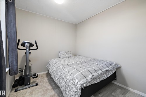 Compact room featuring light-toned walls, wood-finish flooring, and a white ceiling with a flush-mount light fixture - 4908 49 Avenue, Onoway, AB - Indoor Photo Showing Bedroom