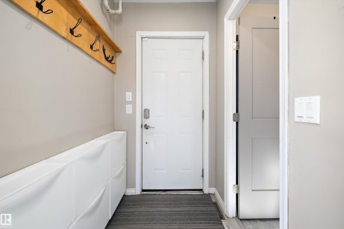 Entryway featuring a white paneled door with smart lock, light gray wall paint, and a built-in wood shelf with black hooks - 4908 49 Avenue, Onoway, AB - Indoor Photo Showing Other Room