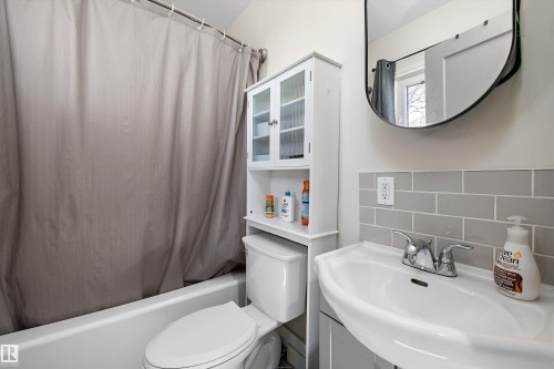 Bathroom featuring a white porcelain toilet, pedestal-style sink with chrome faucet, subway tile backsplash, and a wall-mounted storage cabinet with glass-front doors - 4908 49 Avenue, Onoway, AB - Indoor Photo Showing Bathroom