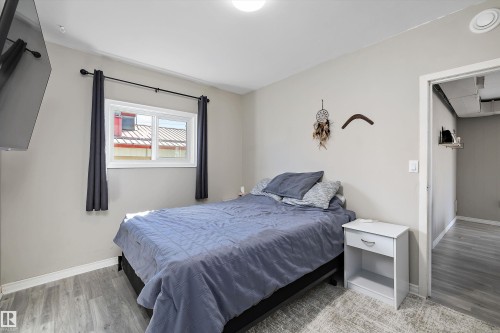 Bedroom featuring light gray walls, wood-finish flooring, a contemporary window with dark curtains, and a built-in overhead light fixture - 4908 49 Avenue, Onoway, AB - Indoor Photo Showing Bedroom