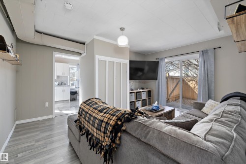 Living area with light wood-finish flooring, a contemporary ceiling fixture, and a sliding glass door - 4908 49 Avenue, Onoway, AB - Indoor Photo Showing Living Room