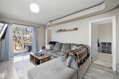 Living area featuring wood-finish flooring, a contemporary ceiling light fixture, and a wall-mounted shelving unit - 4908 49 Avenue, Onoway, AB - Indoor Photo Showing Living Room