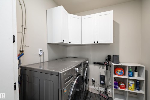Laundry area featuring white shaker-style wall cabinetry, dark wood-finish flooring, and light neutral wall paint - 4908 49 Avenue, Onoway, AB - Indoor Photo Showing Laundry Room