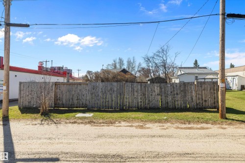 Vacant lot featuring a wooden privacy fence, a grass lawn, and a dirt road frontage - 4908 49 Avenue, Onoway, AB - Outdoor