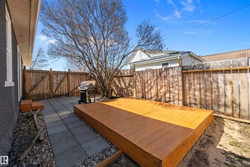 Backyard featuring an elevated wood deck, a paved patio area, natural wood fencing, and a mature tree - 4908 49 Avenue, Onoway, AB - Outdoor
