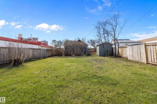 Expansive outdoor space featuring a large grassy lawn, privacy fencing, a gray storage shed, and mature trees - 4908 49 Avenue, Onoway, AB - Outdoor With Backyard