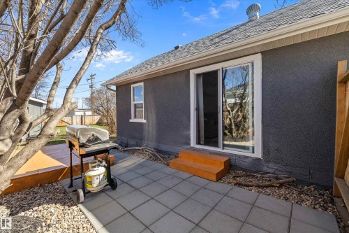 Rear exterior featuring a sliding glass patio door, two-tier wooden steps, a paver patio, and a shingle roof - 4908 49 Avenue, Onoway, AB - Outdoor With Exterior