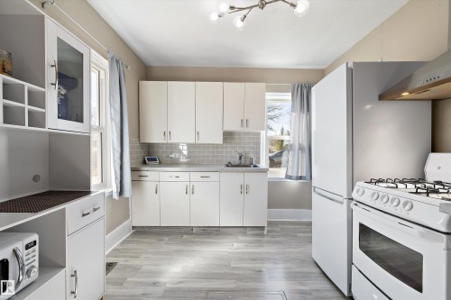 Kitchen featuring light wood-finish flooring, white cabinetry, a subway tile backsplash, and a modern ceiling light fixture - 4908 49 Avenue, Onoway, AB - Indoor Photo Showing Kitchen