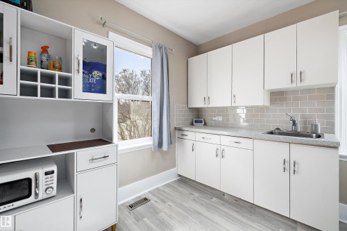 Kitchenette featuring light wood-finish flooring, white cabinetry, a subway tile backsplash, and a stainless steel sink - 4908 49 Avenue, Onoway, AB - Indoor Photo Showing Kitchen