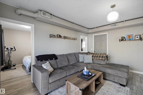 Living area featuring wood-finish flooring, light gray walls, a ceiling-mounted light fixture, and visible ductwork - 4908 49 Avenue, Onoway, AB - Indoor Photo Showing Living Room