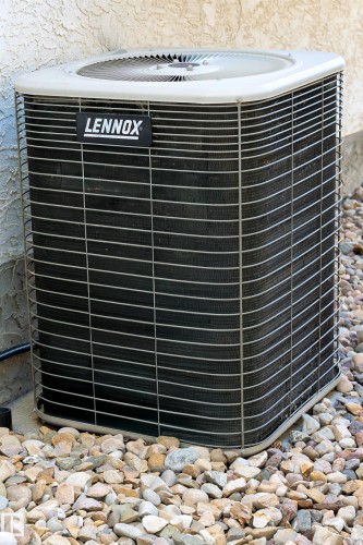 Lennox air conditioning unit situated on a gravel bed with a stucco exterior background - 11686 15 Avenue, Edmonton, AB 