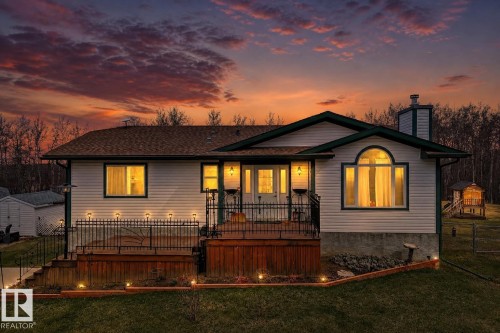 Exterior featuring white siding, dark green trim, a multi-level wooden deck with black metal railings, an arched bay window, and a built-in chimney - 8 54514 Rr12, Rural Lac Ste. Anne County, AB - Outdoor