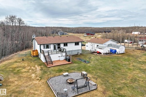 Rear exterior showcasing a multi-level deck with black railing, a stone fire pit area, and a detached garage - 8 54514 Rr12, Rural Lac Ste. Anne County, AB - Outdoor