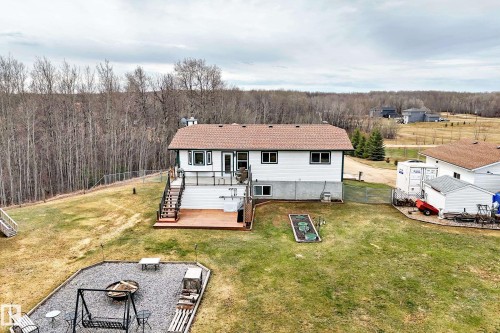 Rear exterior featuring an elevated deck with glass railing, a ground-level patio, and a tiered lawn - 8 54514 Rr12, Rural Lac Ste. Anne County, AB - Outdoor