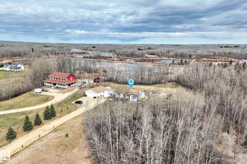 Rural property featuring a red two-story home with a wraparound porch, a detached garage, and a secondary dwelling - 8 54514 Rr12, Rural Lac Ste. Anne County, AB - Outdoor With View