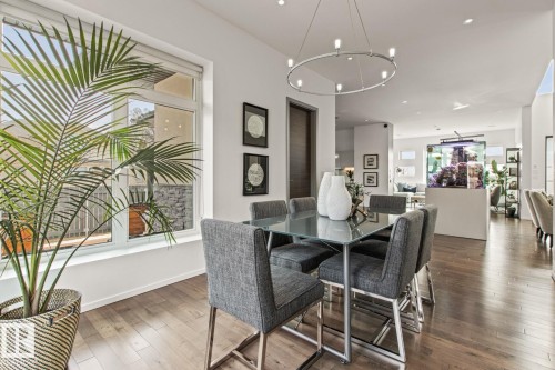 Foyer featuring high ceilings, wood-finish flooring, a contemporary chandelier, a built-in aquarium, and multiple windows - 7548 110 Avenue, Edmonton, AB - Indoor Photo Showing Other Room