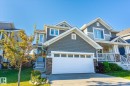 Two-story residence featuring a two-car garage, stone accents, and a covered porch with white railings - 6864 Evans Wynd, Edmonton, AB  - Outdoor With Facade 