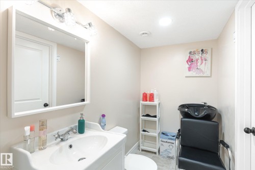Bathroom featuring a white vanity with integrated sink, chrome faucet, and rectangular framed mirror with vanity lighting - 6864 Evans Wynd, Edmonton, AB - Indoor Photo Showing Bathroom