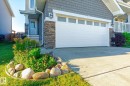 Concrete driveway leading to a two-car garage with transom windows - 6864 Evans Wynd, Edmonton, AB  - Outdoor 