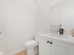 The bathroom features a white vanity with a rectangular sink, a black faucet, and a mirror - 