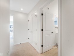 Hallway featuring light-colored carpet flooring, white walls, and a recessed ceiling light - 