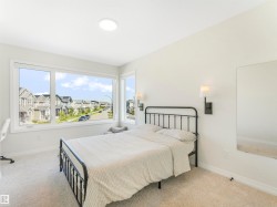 This room features light-colored walls and carpet, a large window providing ample natural light and views of the surrounding neighborhood, and a ceiling light fixture - 