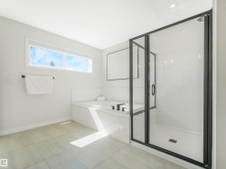 The bathroom features a built-in bathtub, a walk-in shower with a glass enclosure, and a horizontal window - 