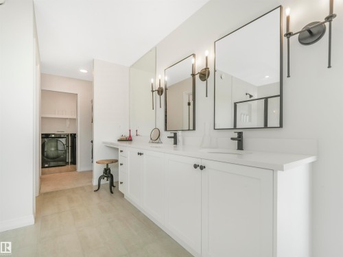 This bathroom features a double vanity with white cabinetry, a light-colored countertop, and two mirrors with black frames - 19 Nettle Crescent, St. Albert, AB - Indoor