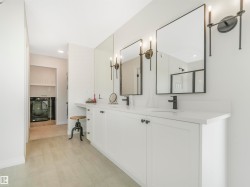 This bathroom features a double vanity with white cabinetry, a light-colored countertop, and two mirrors with black frames - 