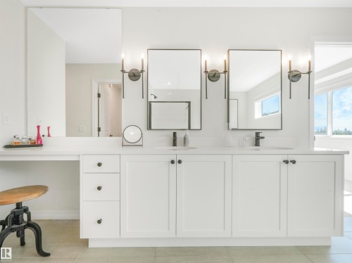 The bathroom features a double vanity with white cabinetry, black hardware, and two framed mirrors illuminated by wall-mounted sconces - 19 Nettle Crescent, St. Albert, AB - Indoor Photo Showing Other Room