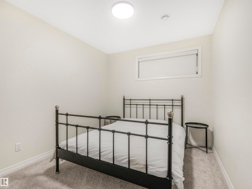 This room features light-colored walls and carpeting, a window with a roller blind, and a ceiling-mounted light fixture - 19 Nettle Crescent, St. Albert, AB - Indoor Photo Showing Bedroom