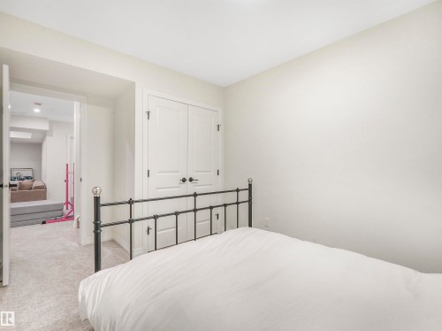 This room features light-colored carpeting and a set of white double doors with black hardware - 19 Nettle Crescent, St. Albert, AB - Indoor Photo Showing Bedroom