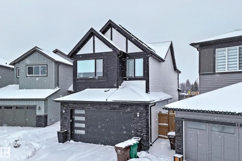The property features a modern exterior with dark siding and white trim accents, a two-car garage with a contemporary door design, and multiple windows across the facade - 19 Nettle Crescent, St. Albert, AB - Outdoor