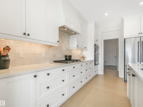 The kitchen features white cabinetry with black hardware, a light-colored tile backsplash, and a gas range - 19 Nettle Crescent, St. Albert, AB - Indoor Photo Showing Kitchen With Upgraded Kitchen