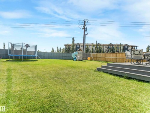 The property features an expansive lawn, a privacy fence, and a multi-tiered deck with ample space for outdoor seating - 19 Nettle Crescent, St. Albert, AB - Outdoor