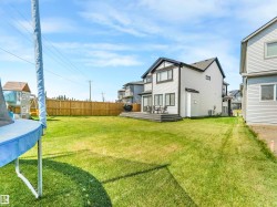 The property features a spacious rear yard with a well-maintained lawn and a wooden fence along the perimeter - 