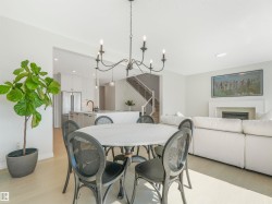 Bright dining area featuring a round table with a white top, dark chairs, and an overhead chandelier, all set on light-colored flooring - 