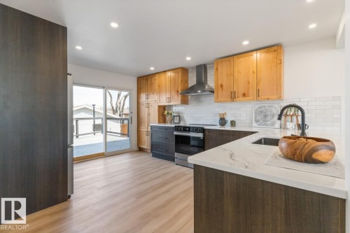 Modern kitchen featuring a light wood-finish floor, white subway tile backsplash, and recessed lighting - 4508 109A Avenue, Edmonton, AB - Indoor Photo Showing Kitchen With Upgraded Kitchen