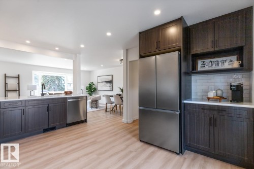 Modern kitchen featuring wood-finish flooring, dark wood cabinetry, stainless steel appliances, and recessed lighting - 4508 109A Avenue, Edmonton, AB - Indoor Photo Showing Kitchen
