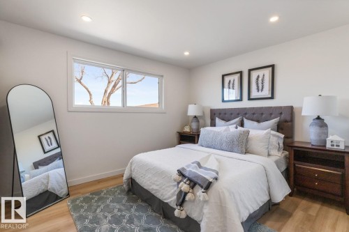 Bedroom featuring recessed lighting, a wide window with white trim, a tufted upholstered headboard, and wood-finish flooring - 4508 109A Avenue, Edmonton, AB - Indoor Photo Showing Bedroom